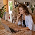 Smiling woman working remotely on a laptop in a bright modern home office
