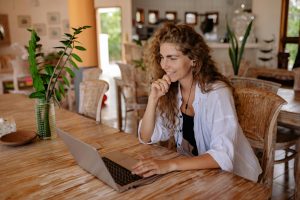 Smiling woman working remotely on a laptop in a bright modern home office