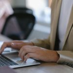 Professional typing on laptop at desk in modern office setting
