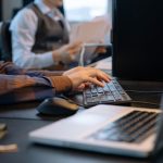 Office worker typing at a desktop computer beside a laptop