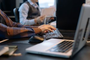 Office worker typing at a desktop computer beside a laptop