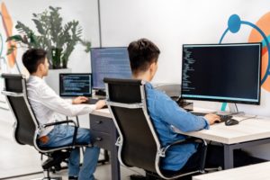 Software developers coding at computers in a modern office